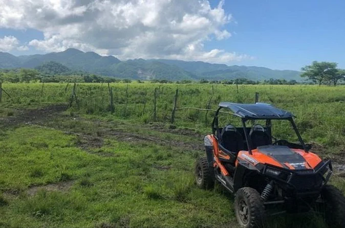 Un buggy côte à côte garé dans la campagne verdoyante sous des montagnes